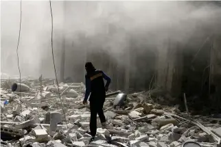  ??  ?? DIRECT HIT: A man walks on the rubble of damaged buildings after an airstrike on the rebel held Al-Qaterji neighborho­od of Aleppo, Syria on Sunday. (Reuters)