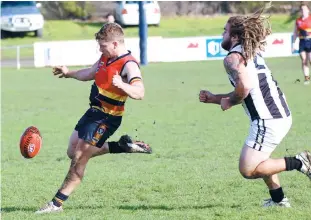 ??  ?? Longwarry’s Josh Bourke kicks into attack as Poowong’s Harley Robjant gives chase