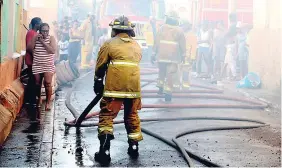  ??  ?? Firefighte­rs roll out hoses to extinguish flames on Rosemary Lane in downtown Kingston.