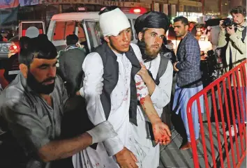  ?? Reuters ?? Two men support an injured victim as they lead him into a hospital following a suicide attack in Kabul yesterday.