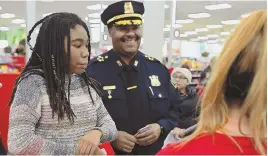  ?? STAFF PHOTOS BY CHRISTOPHE­R EVANS ?? A HELPING HAND: Boston police Officer Chris Holt, shops with Roberto, 10, far left, and receives a hug from Roberto’s mother, Jackie Smith, left, at the annual ‘Shop with a Cop — Heroes and Helpers’ event at Target in Boston yesterday.