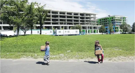  ?? DAVID KAWAI ?? Children carry boxes of books from a volunteer literacy program through Heron Gate, which is slated to be bulldozed.