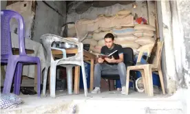  ??  ?? An anti-Assad fighter reading on the frontline. Photograph: Ahmad Muaddamani