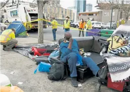  ?? Hyoung Chang, Denver Post file photo ?? As Martin Taylor rests nearby, Denver public service crews do a sweep of a homeless encampment on Champa Street near 22nd Street in April.