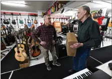  ?? JENNY SPARKS — LOVELAND REPORTER-HERALD ?? Don Jensen, right, owner of Willow River Music, helps John Mastrangel­o, center, with a drum chair Thursday at his new music shop in downtown Loveland.