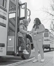  ?? BRIAN MUNOZ/USA TODAY ?? Olivia Jones-Martin, a prekinderg­arten instructio­nal aid, helps students get off the bus on Feb. 1 at Parrish Elementary School in Carbondale, Ill. The school is taking various precaution­s, such as limited classroom sizes and social distancing, to prevent the spread of the novel coronaviru­s.