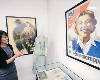  ??  ?? Sue Wilkins, director of education at The Internatio­nal Museum of World War II, in Natick, Mass., stands near a 1933 propaganda poster that praises the Nazi organizati­on German Labour Front, which was created after the Nazis eliminated trade unions. A...