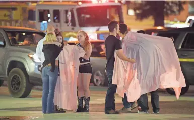  ?? MARK J. TERRILL/AP ?? People comfort each other as they stand near the scene Thursday in Thousand Oaks, California, where a gunman opened fire Wednesday inside a country dance bar crowded with hundreds of people on “college night,” killing 12 people, including a deputy who rushed to the scene.