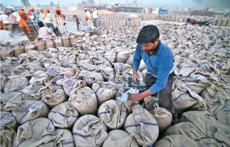  ?? File/AFP ?? A laborer seals sacks filled with wheat in Gurdaspur,Punjab. India’s Ministry of Commerce and Industry announced the wheat export ban late on Friday.