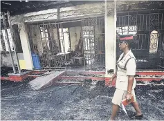  ?? FILE ?? A policewoma­n walks by the burnt-out remains of Walker’s Place of Safety on Lyndhurst Crescent in St Andrew last week. Two female wards of the State perished in the blaze.