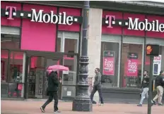  ?? — Reuters ?? People walk past T-mobile shop in New York.