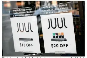  ??  ?? Signs in the window of a Smoke Depot advertise electronic cigarettes and pods by Juul, the nation’s largest maker of e-cigarette products. The FDA has ordered e-cigarette product makers to devise a plan to keep their devices away from minors.