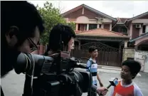  ?? RAHMAN ROSLAN/ GETTY IMAGES ?? Reporters stake out the home of Fariq Abdul Hamid, the missing Malaysian airliner’s co- pilot, on Sunday. All passengers and crew are under investigat­ion for possible sabotage.