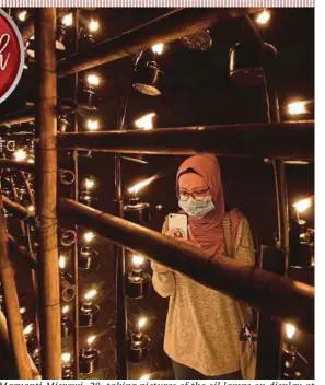 ?? BERNAMA PIC ?? Maryanti Misrawi, 28, taking pictures of the oil lamps on display at Kampung Ribut in Padang Rengas recently.