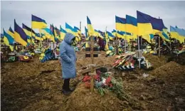  ?? EVGENIY MALOLETKA/AP ?? The wife of slain Ukrainian serviceman Serhiy Klymenko stands by his grave Friday in Kharkiv, Ukraine. Klymenko was killed by Russian shelling earlier in the week.