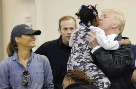 ?? SUSAN WALSH — THE ASSOCIATED PRESS ?? President Donald Trump and Melania Trump meet people Saturday affected by Tropical Storm Harvey during a visit to the NRG Center in Houston. Here he lifts this girl into his arms to give her a kiss. It was his second trip to Texas in a week.