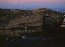  ?? Associated Press ?? A man looks out at wind turbines in California on a recent day.