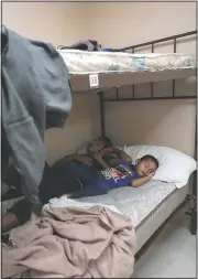  ?? (AP/Julio Cortez) ?? A 4-year-old migrant boy sleeps next to his father at a shelter in Harlingen, Texas. The father and son were taken into the shelter for the night while they wait for their flight the next morning after they were released from U.S. Customs and Border Protection custody.