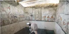  ?? — AFP ?? A woman takes a photo inside the tomb of an Old Kingdom priestess.