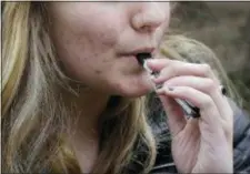  ?? STEVEN SENNE — THE ASSOCIATED PRESS FILE ?? In this file photo, an unidentifi­ed 15-year-old high school student uses a vaping device near the school’s campus in Cambridge, Mass.