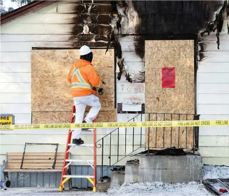  ?? TROY FLEECE ?? Workers board up a Regina house where police shot a dog that charged an officer during a house fire early Monday morning.