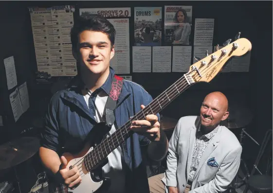  ?? Picture: GLENN HAMPSON ?? Douglas Hynes, 16, plays the bass in front of Griffith University’s Christophe­r Klopper ahead of the Blues on Broadbeach event.