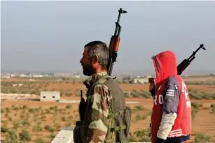  ?? (AFP/Getty) ?? Turkey - backed Syrian fighters stand guard c l ose to the border with Turkey in rebe l- he l d northern Syria