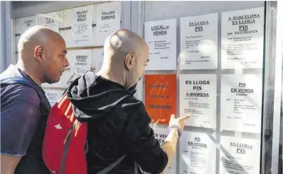  ?? Oscar Bayona ?? Dos hombres consultan anuncios de pisos en una inmobiliar­ia en Manresa.