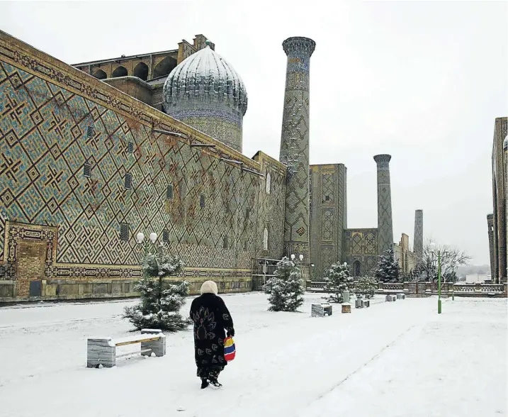  ?? Picture: Getty Images ?? TRADE ROOTS A woman walks through the snow in The Registan, a medieval square in the heart of the ancient city of Samarkand, Uzbekistan.