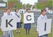  ?? (AFP) ?? Schoolgirl­s, working as volunteers, hold placards to help guide people ahead of a ceremony with Pope Francis in Hiroshima on Sunday