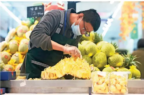  ?? FOTO: LONG WEI/DPA ?? Auch in China sind Durians beliebt: Ein Supermarkt-angestelle­r in Hangzhou sortiert die importiert­en Früchte vor dem Verpacken.