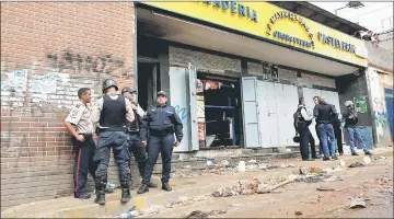  ??  ?? Police officers and criminal investigat­ors stand in front of a bakery, after it was looted in Caracas, Venezuela. — Reuters photo