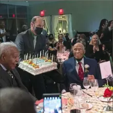  ?? Emily Matthews/Post-Gazette ?? Pitt Olympian Herb Douglas did a little dance in his seat after blowing out the candles on his birthday cake at the Senator John Heinz History Center. Douglas turned 100 on March 9.