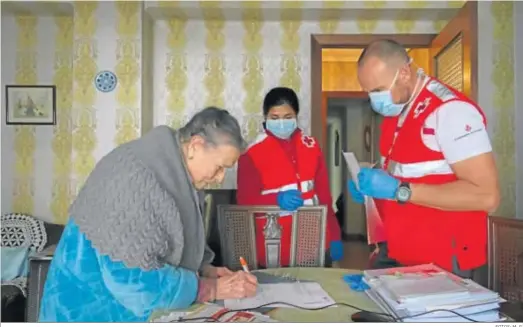  ?? FOTOS: M. G. ?? Una mujer firma un documento en presencia de voluntario­s de la Cruz Roja.