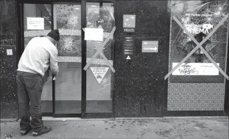  ?? MUSTAFA YALCIN / ANADOLU AGENCY VIA GETTY IMAGES ?? A worker covers the windows of a vandalized BNP Paribas bank branch in Paris on Thursday, to prepare for a “yellow vest” demonstrat­ion on Saturday.