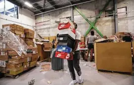  ??  ?? Tre Cadwell, 22, carries sneakers to a station to be authentica­ted at the new Stock X facilites in Detroit.