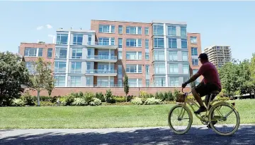  ??  ?? A cyclist makes his way past a building in Alexandria,Virginia, that contains a unit listed to Manafort. — Reuters photo