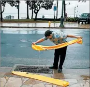  ?? JOHN LOCHER/AP ?? Kevin Pak empties hydro barriers, used to block water similar to a sandbag, as he helps reopen a store Saturday along Waikiki Beach in Honolulu. Lane veered from the islands.