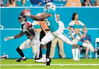  ?? JIM RASSOL/STAFF PHOTOGRAPH­ER ?? Leonte Carroo of the Dolphins hauls in a touchdown pass against Atlanta’s C.J. Goodwin in Thursday’s preseason game at Hard Rock Stadium.