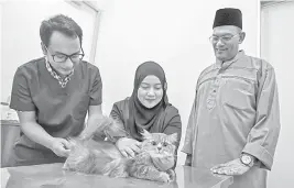  ?? — Gambar Bernama ?? POPULASI LEBIH TERKAWAL: Khalid (kanan) melihat Pengurus Vet O Vet Kota Bharu Dr Hafizie Mahadi (kiri) melakukan pemeriksaa­n kesihatan ke atas seekor kucing pada Hari Bertemu Vet Dr Kucing dan Beraya Bersama Si Comel di Wisma Bakti, Pengkalan Chepa di Kota Bharu baru-baru ini.