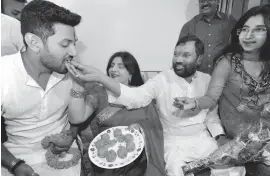  ?? — PTI ?? LJP president Ram Vilas Paswan offers sweets to his son Chirag Paswan, who won in the Lok Sabha polls, in Patna on Friday.