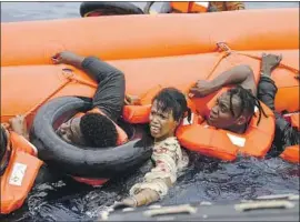  ?? Valeria Mongelli Associated Press ?? MIGRANTS who were aboard a precarious rubber boat grab a f loat as they are rescued by a team from a Sea-Watch ship about 35 miles off Libya last week.