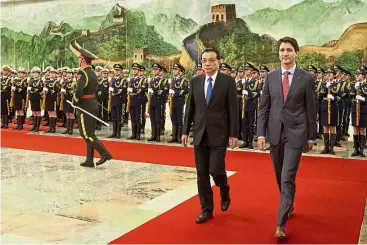  ?? — AP ?? Making an entrance: Trudeau walking alongside Li during a welcoming ceremony at the Great Hall of the People in Beijing.