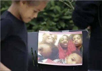  ?? PHOTO AP ?? A neighbor girl walks past a memorial outside where a pregnant mother was shot and killed a day earlier at her apartment by police June 19 in Seattle.