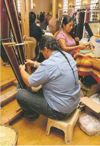  ??  ?? ABOVE: Darnell Lewis of Pojoaque Pueblo demonstrat­es weaving traditiona­l pueblo attire next to his wife, Paula.