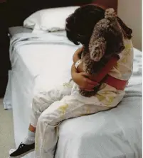  ?? Betty Tichich / Staff file photo ?? A mentally ill child cuddles a teddy bear in the children’s unit at Harris County Psychiatri­c Center in 1989.