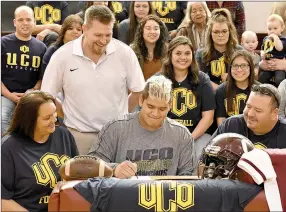  ?? Bud Sullins/Special to the Herald-Leader ?? Oaks-Mission (Okla.) senior lineman Joseph “Choogie” Young signed a letter of intent Friday to play football at the University of Central Oklahoma in the Oaks gymnasium. Also pictured are his mother, Penny, left, and father, Chero, right, Oaks head...