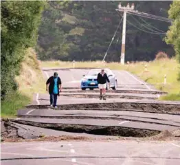  ??  ?? Residents Chris and Viv Young look at damage caused by the earthquake along State Highway One near the town of Ward in Blenheim, South Island, yesterday.