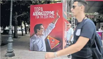  ??  ?? Un griego camina frente a una propaganda del primer ministro, Alexis Tsipras, en Atenas.