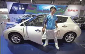  ?? MARK SCHIEFELBE­IN/AP FILE ?? A staff member climbs out of an electric car from Chinese automaker Venucia at the Beijing Internatio­nal Automotive Exhibition in April 2016. China is violating its free-trade pledges, a business group said Tuesday.